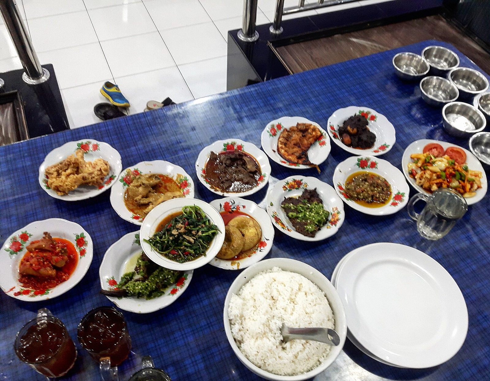 A Padang-style plate set with rendang, sambal, and small bowls.