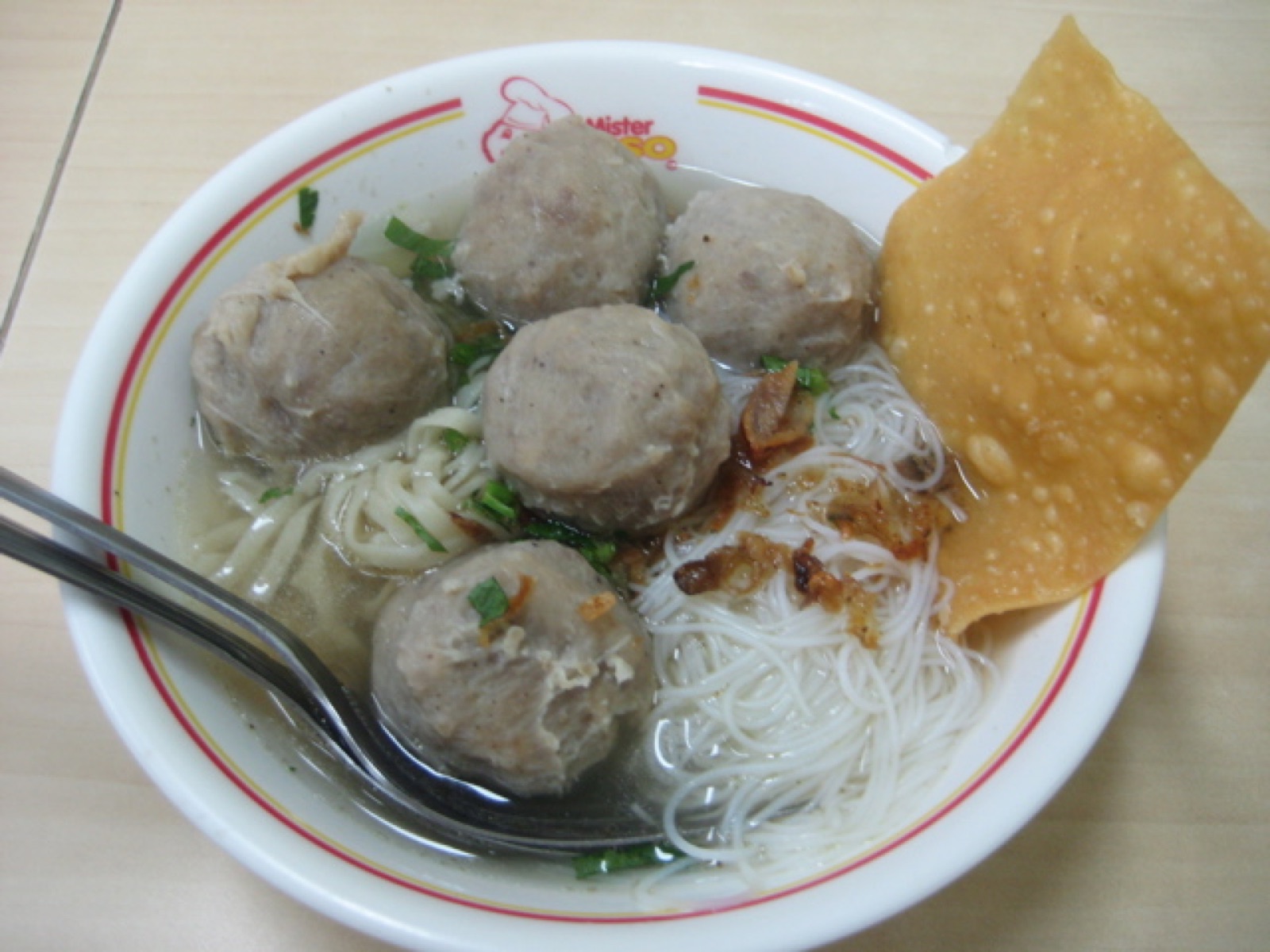 A bowl of bakso with meatballs, noodles and clear broth.