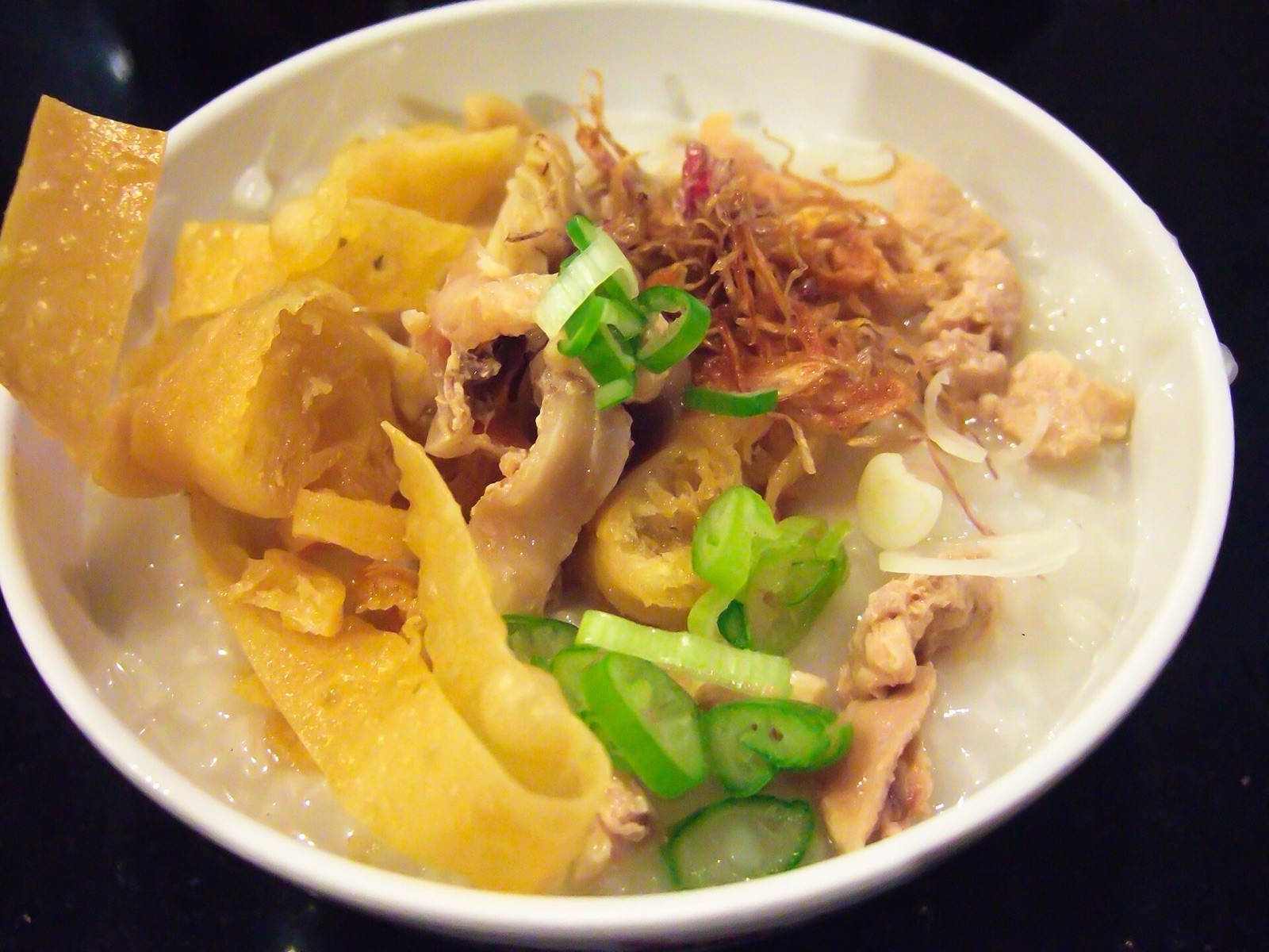 A bowl of chicken porridge with toppings.